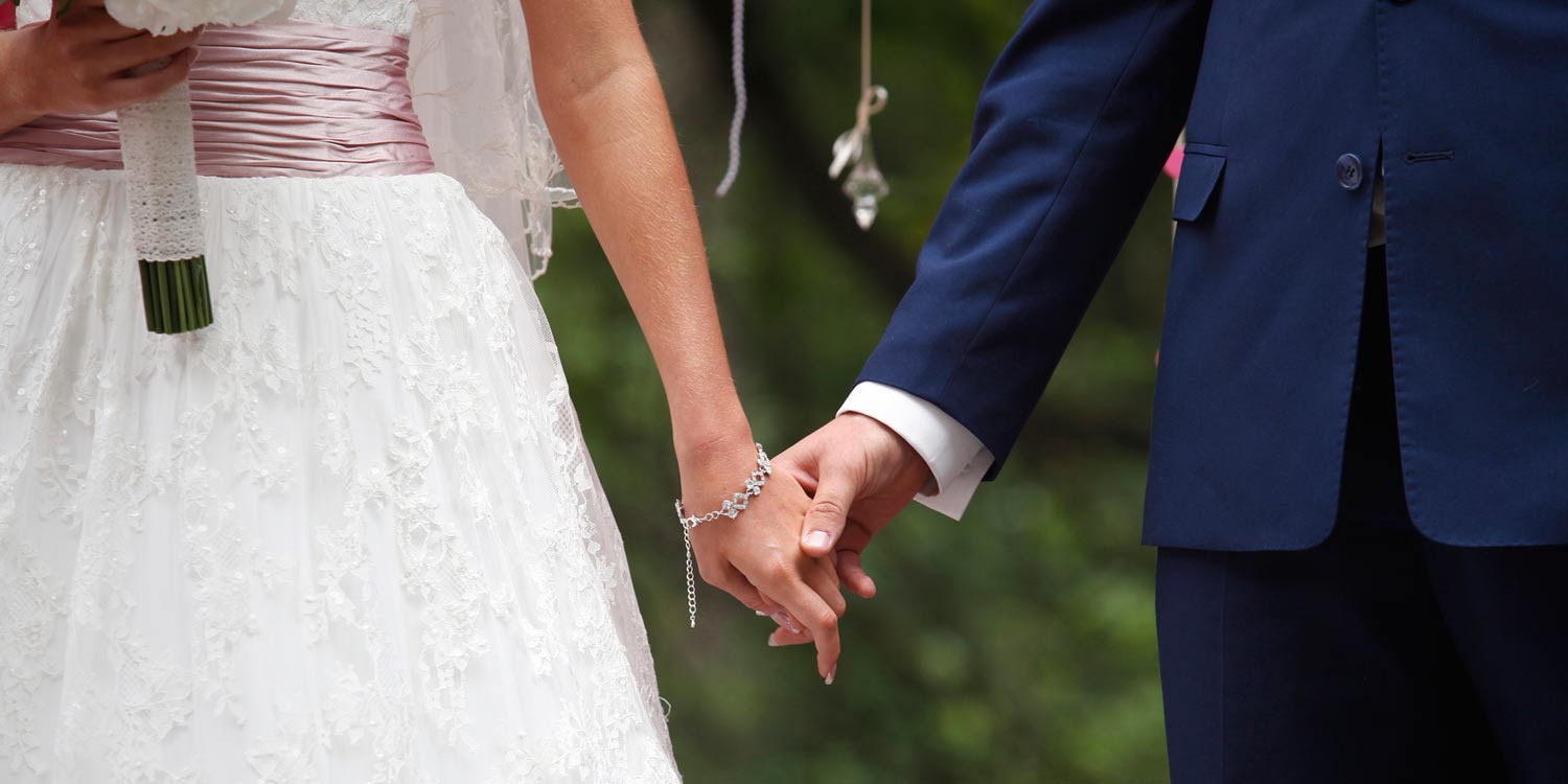Bride and groom holding hands, representing binding financial agreement