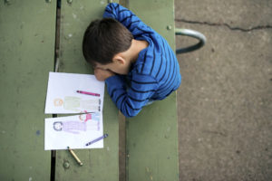 De facto property settlement concept -Young boy looking sad at drawing of a broken family